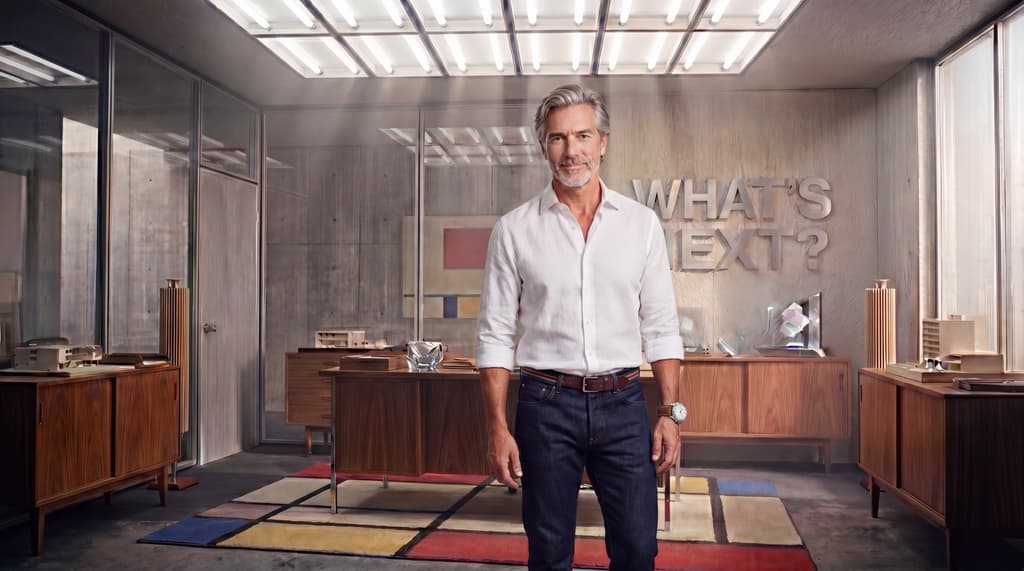 The What&rsquo;s Next host standing in a mid-century office, a Mondrian rug underfoot and &lsquo;What&rsquo;s Next?&rsquo; on the wall behind.